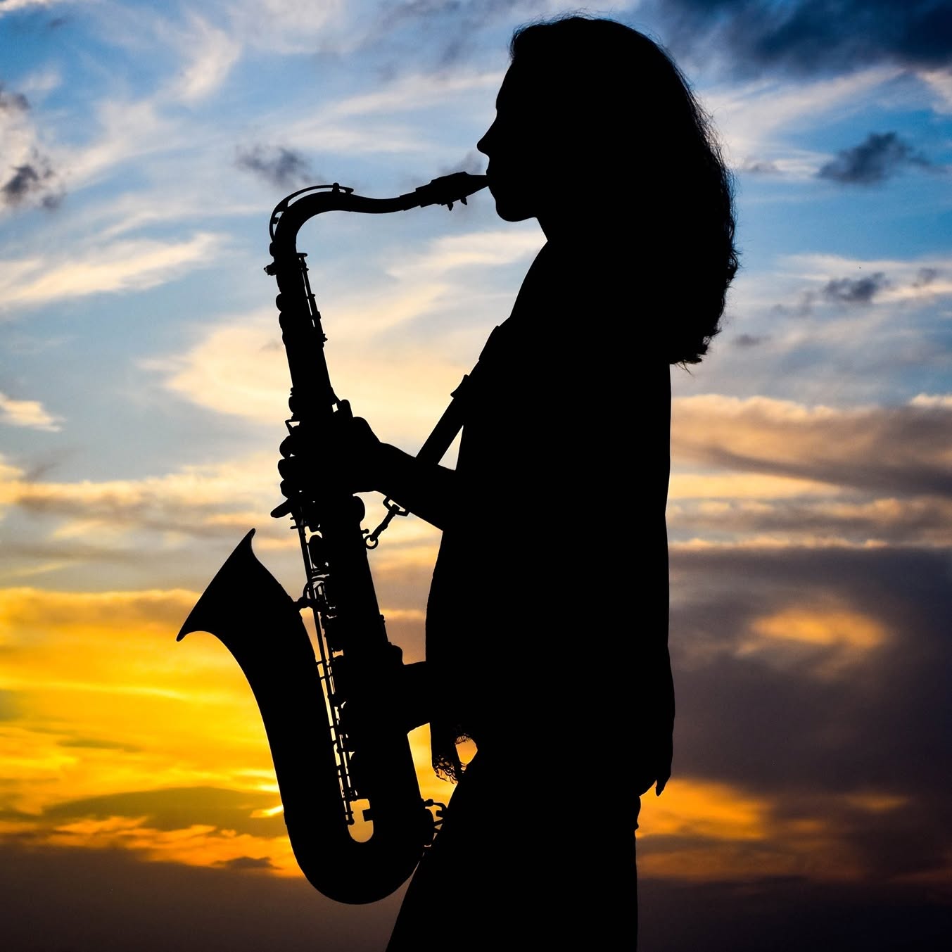 Silhouette of Amy Cyr playing saxophone against a Southwest Florida sunset