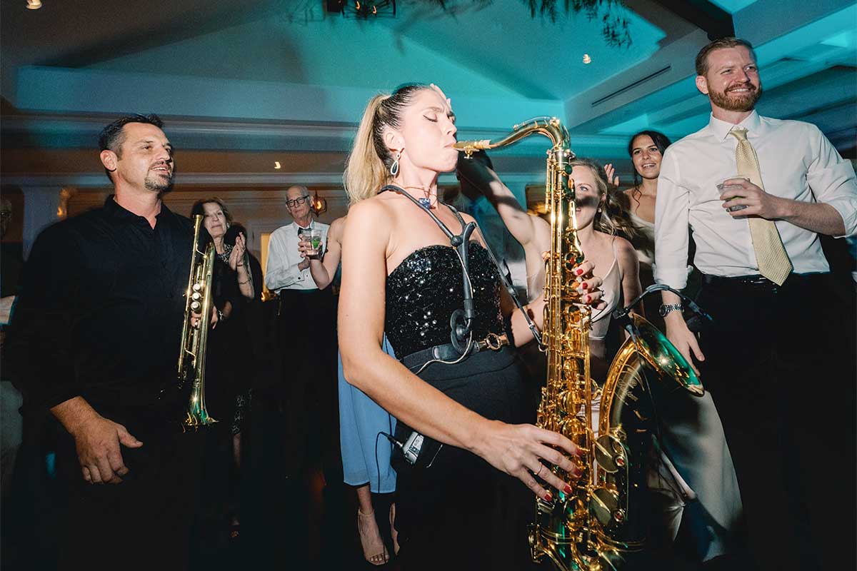 Amy Cyr playing saxophone on the floor among guests at an evening event