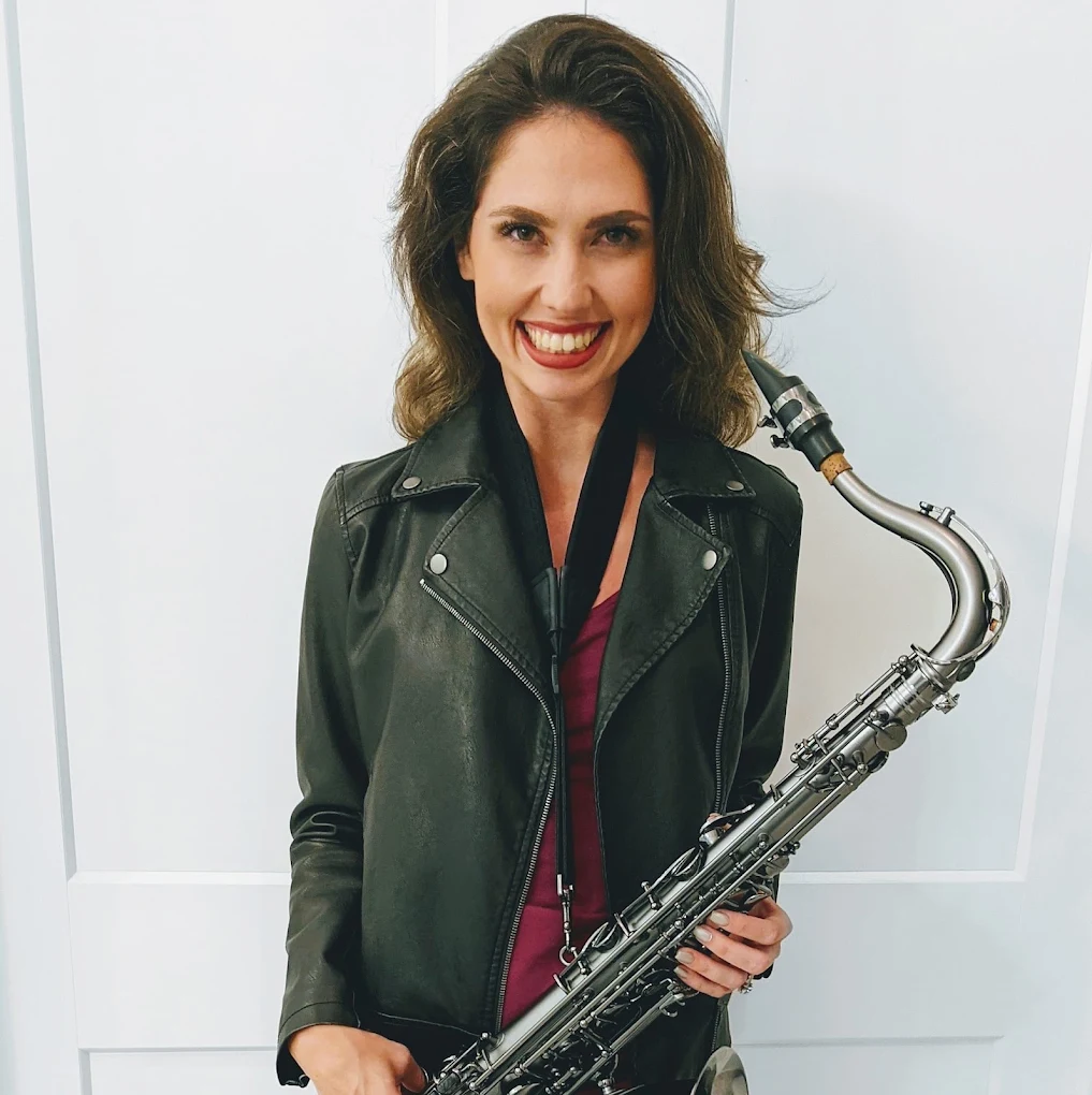 Amy Cyr smiling warmly while holding her saxophone